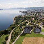 Dronefoto av nybygg i front, med utsikt over Gjøvik og Mjøsa