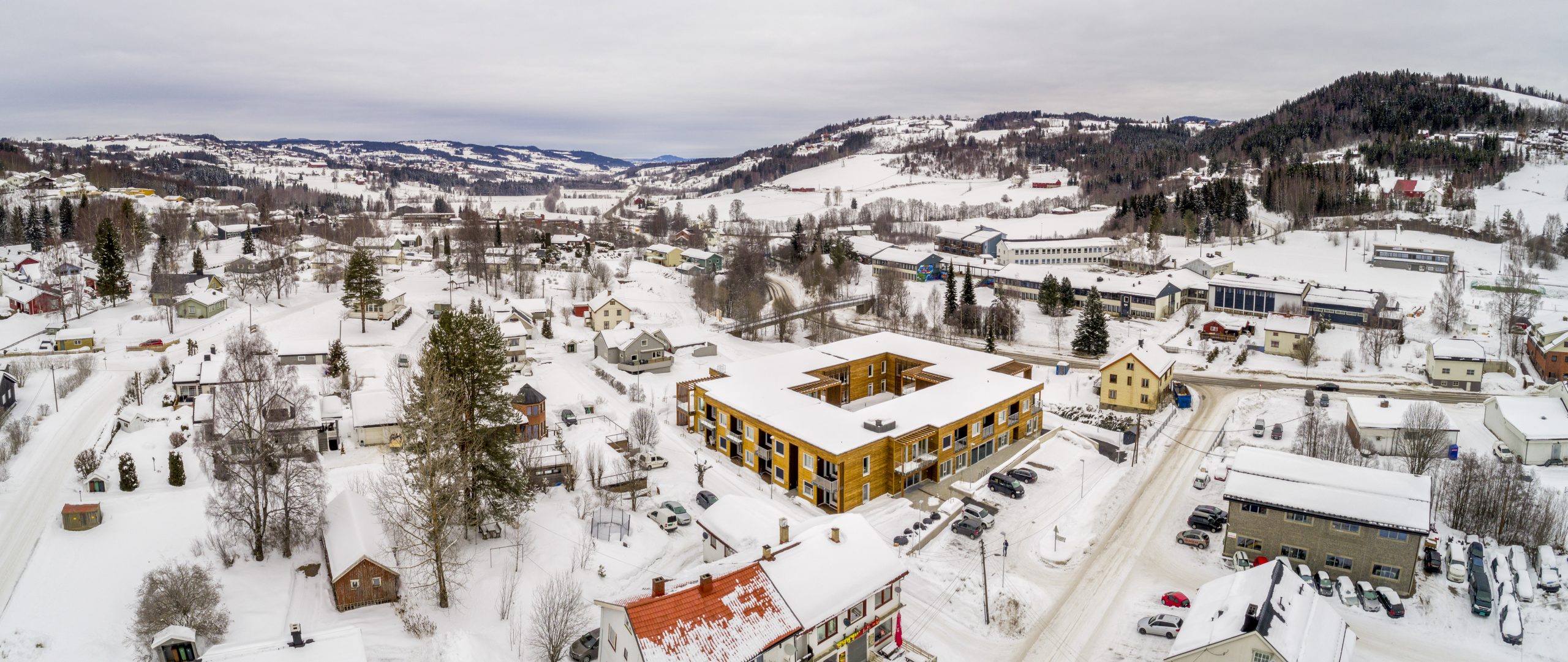 Dronefoto av et kvadratisk bygg med trefasade