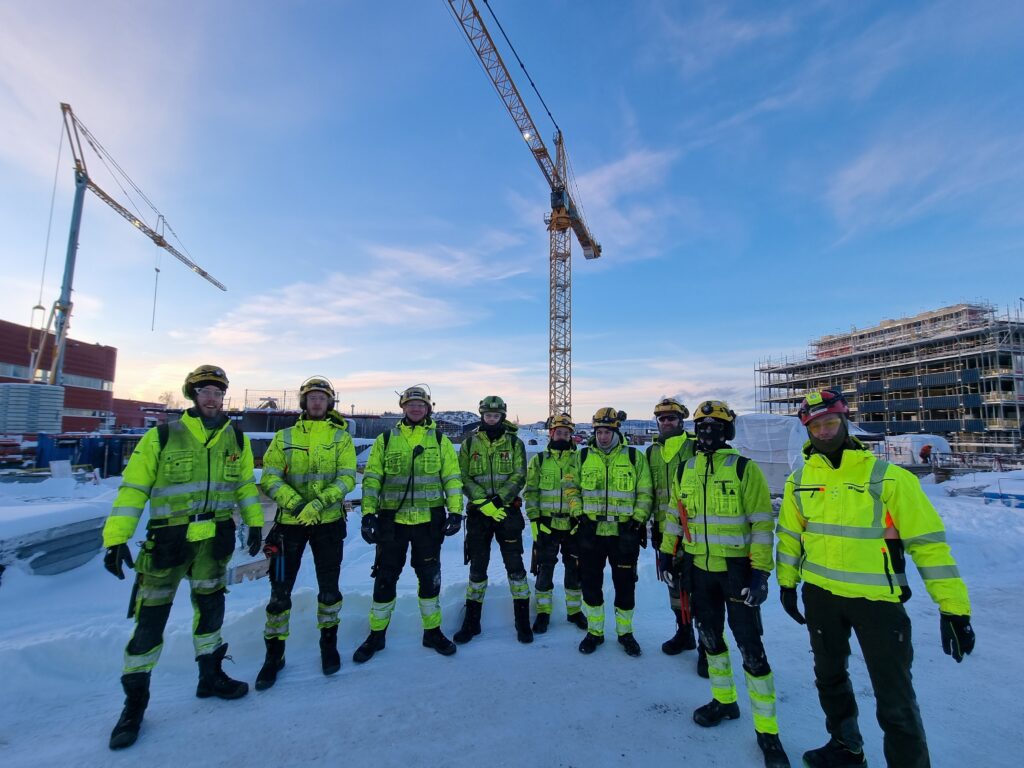 Menn i verneutstyr, utendørs, byggeplass, byggekran, blå himmel